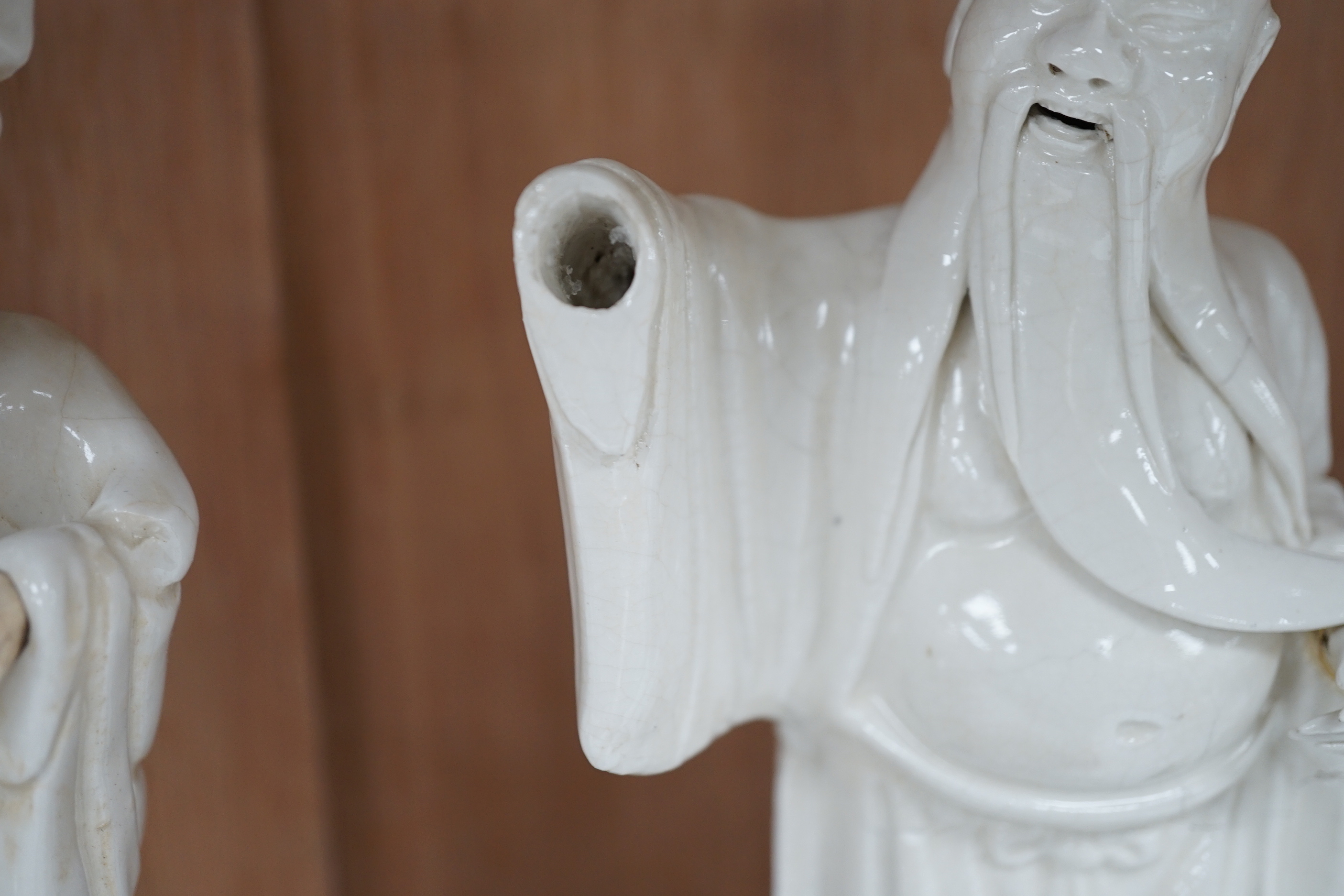 Seven Chinese blanc de Chine figures of immortals, each raised on carved hardwood bases, the largest 24cm high